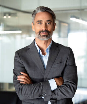 istockphoto-1949501832-612x612 Handsome hispanic senior business man with crossed arms smiling at camera. Indian or latin confident mature good looking middle age leader male businessman on blur office background with copy space.